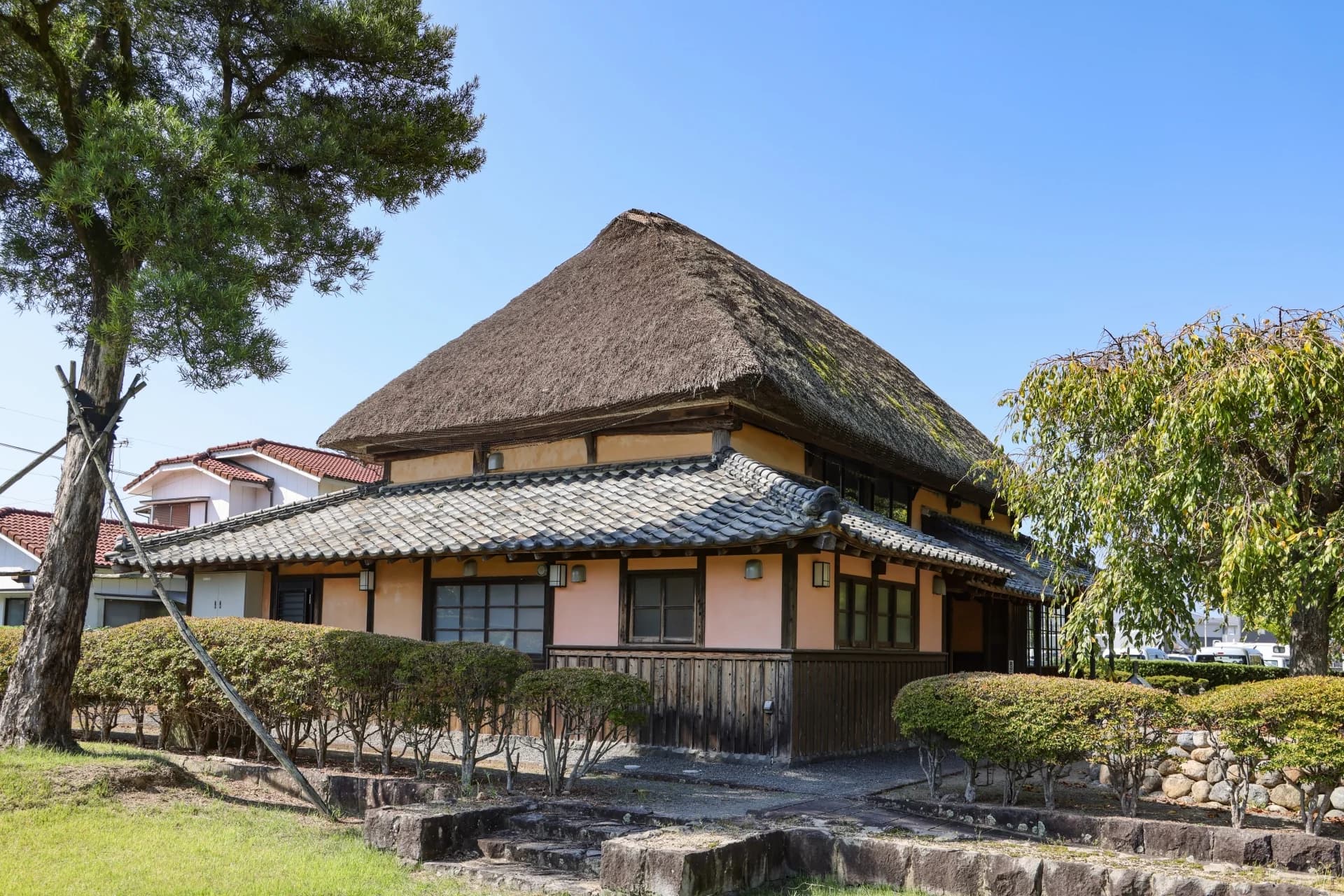 茅葺き屋根に瓦のひさしを回した明治時代の民家