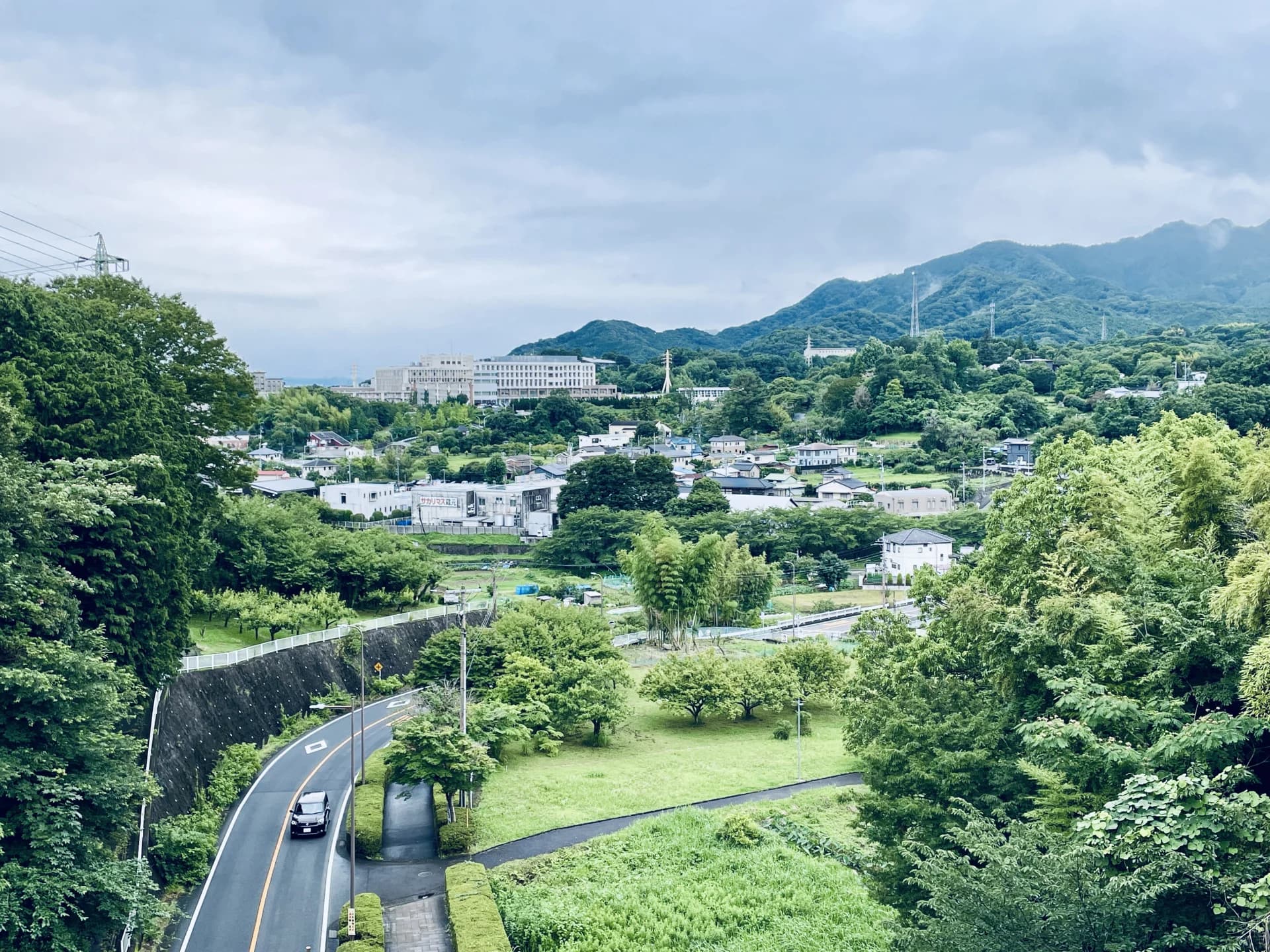 山あいの七沢で緑の丘陵と山並みを背に戸建て住宅が点在する厚木市の街並み（厚木市の空き家買取のイメージ）