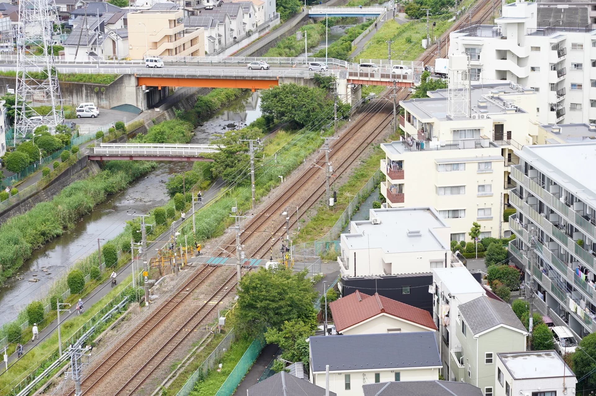町田の線路と川沿いに戸建て住宅とマンションが建ち並ぶ住宅街の俯瞰（町田市の空き家買取のイメージ）