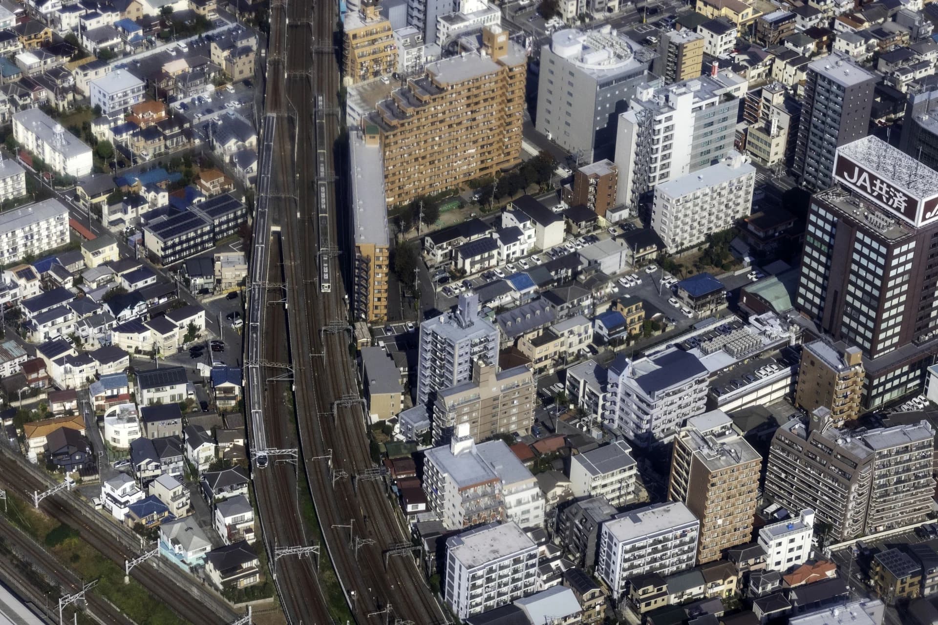 線路沿いに戸建て住宅と中高層マンションが密集する大宮区土手一丁目付近を上空から見た街並み（さいたま市の空き家買取のイメージ）