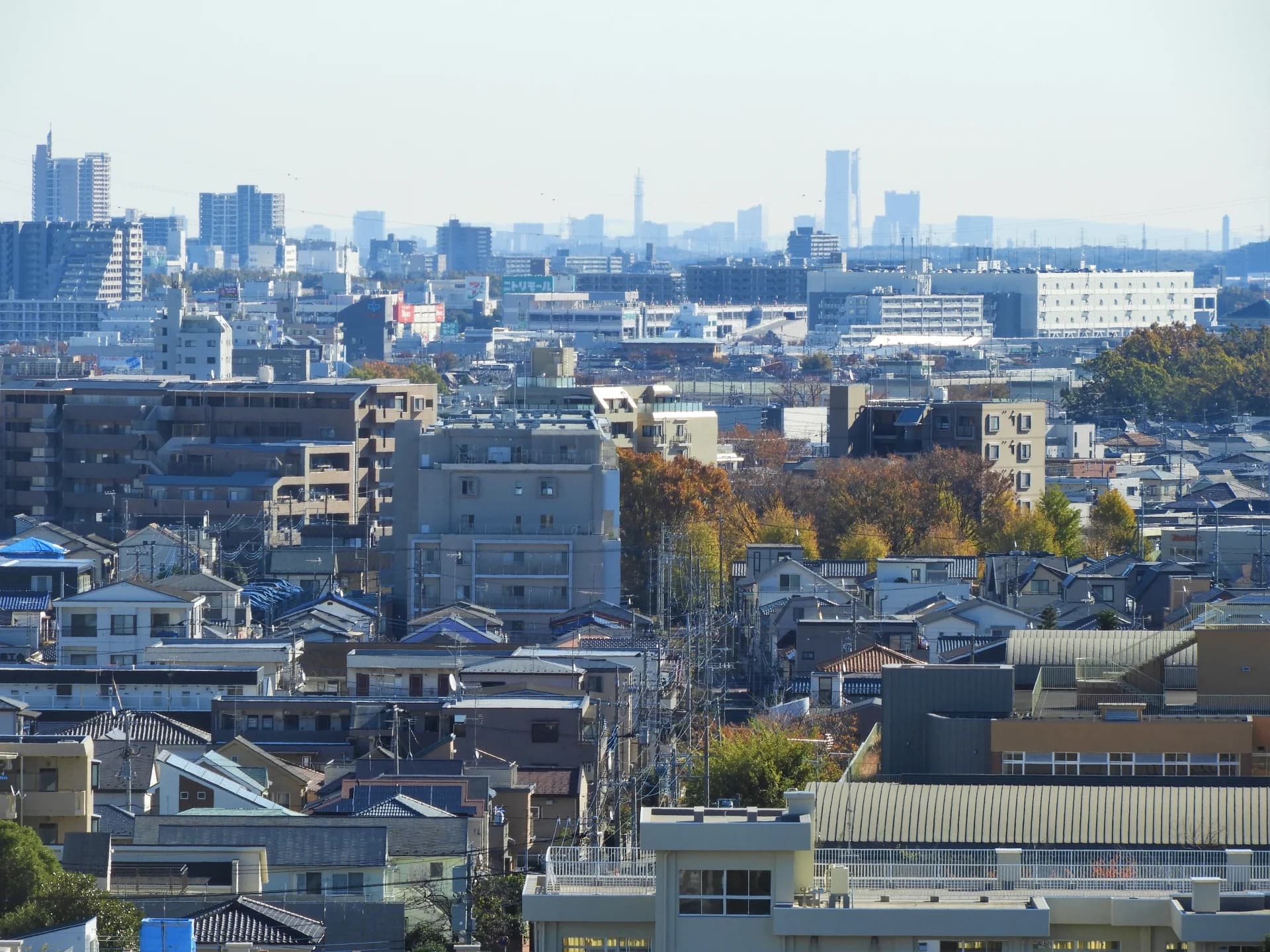 相模原の市街地で戸建て住宅と集合住宅が連なり遠くに横浜の高層ビルが見える街並み（相模原市の空き家買取のイメージ）