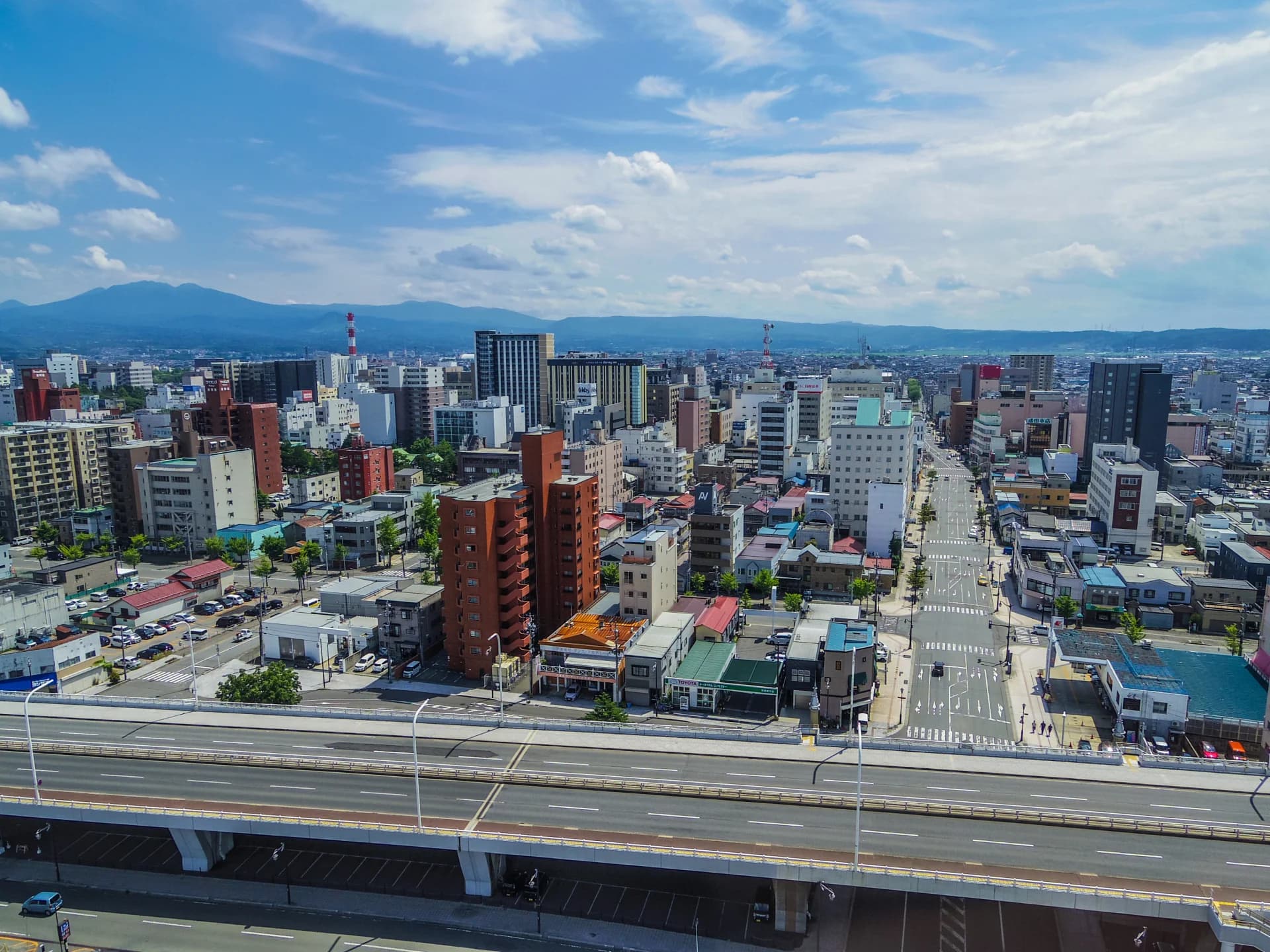 住宅やビルが建ち並ぶ青森市街地と遠くの八甲田連峰（青森の共有持分の買取のイメージ）