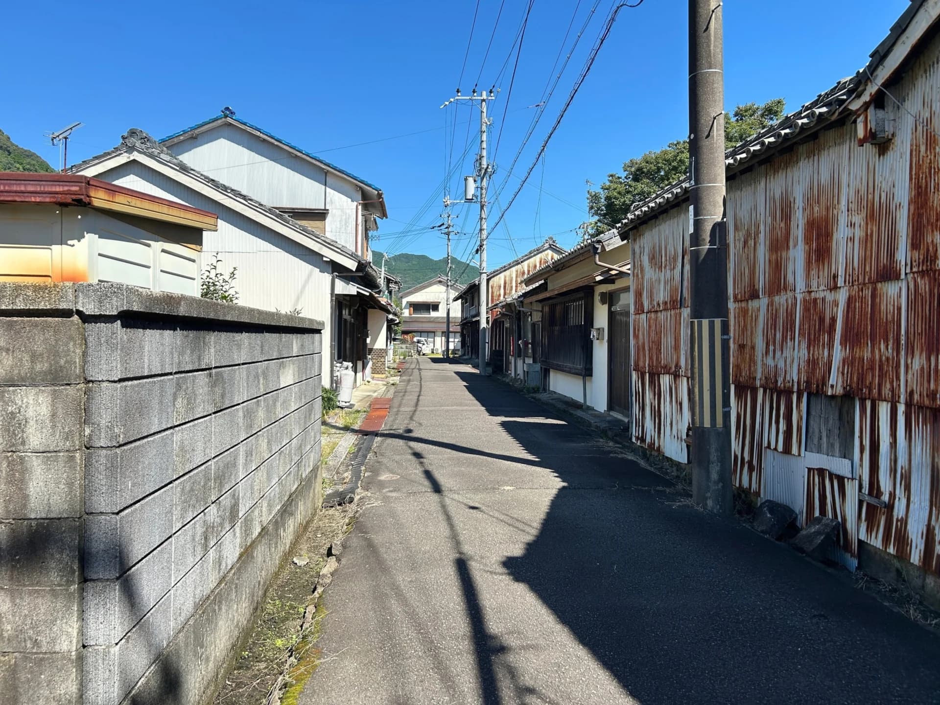トタン張りの古い木造住宅とブロック塀が並ぶ細い道（埼玉の再建築不可物件の買取のイメージ）