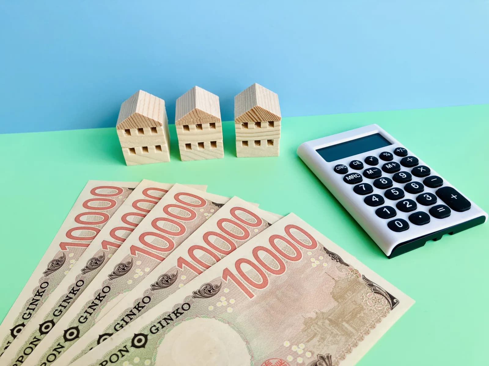5万円と電卓と3軒の家(不動産の税金に関する記事のイメージ)
