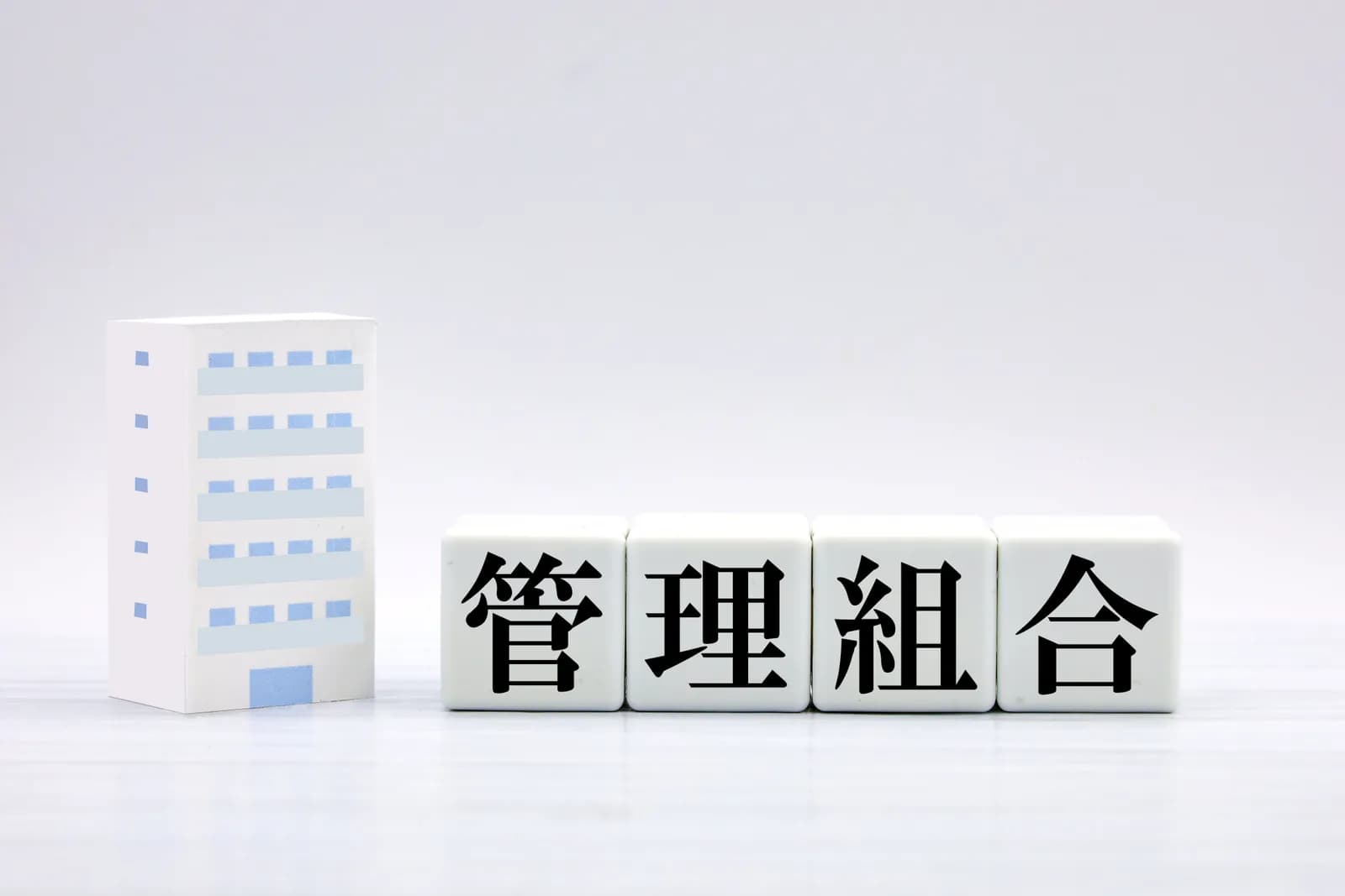 マンションの模型と「管理組合」の文字ブロック(親のマンションの処分に関する記事のイメージ)