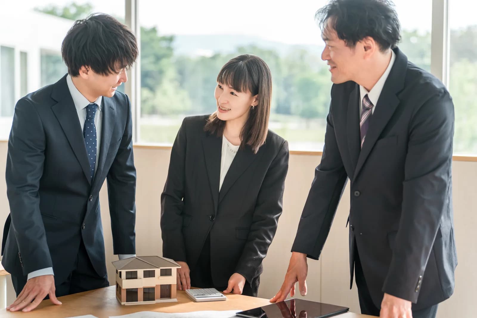 住宅模型を使ってミーティングをする男女(相続・登記に関する記事のイメージ)