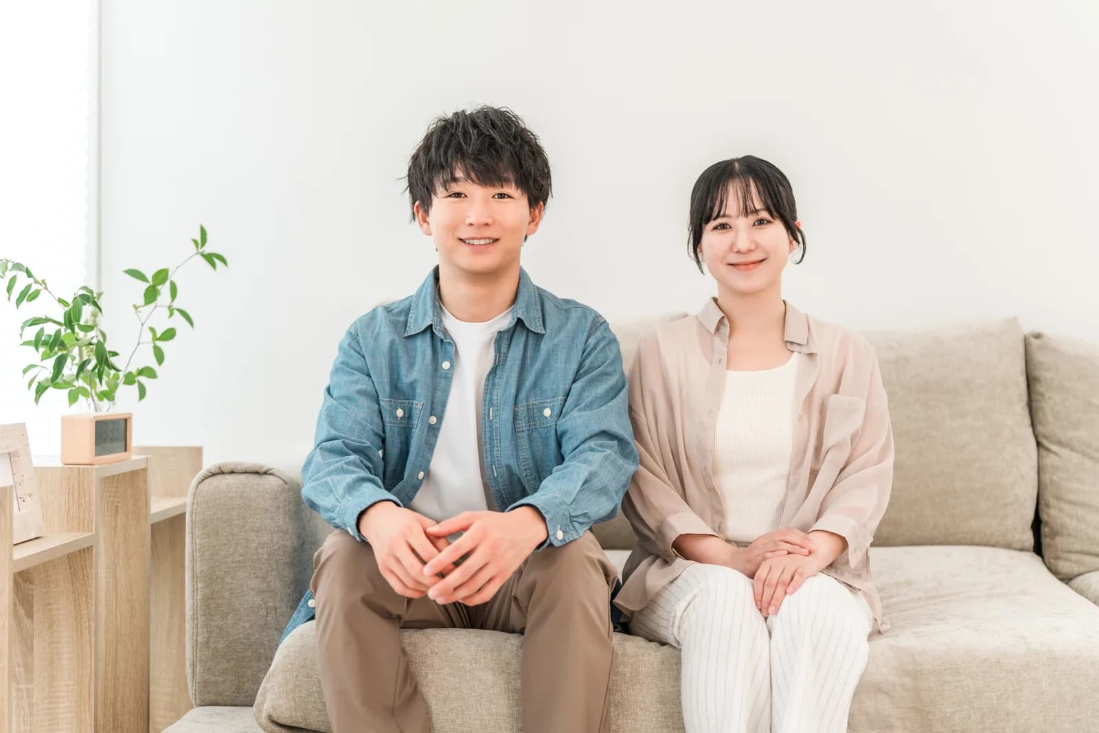 家のリビングでソファーに座る若い夫婦(不動産買取業者に関する記事のイメージ)