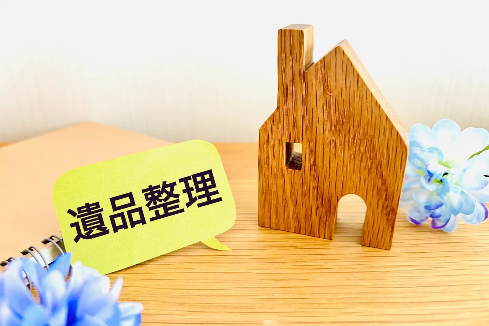 木の家の置物と「遺品整理」の吹き出し(親の死後の家の処分費用に関する記事のイメージ)