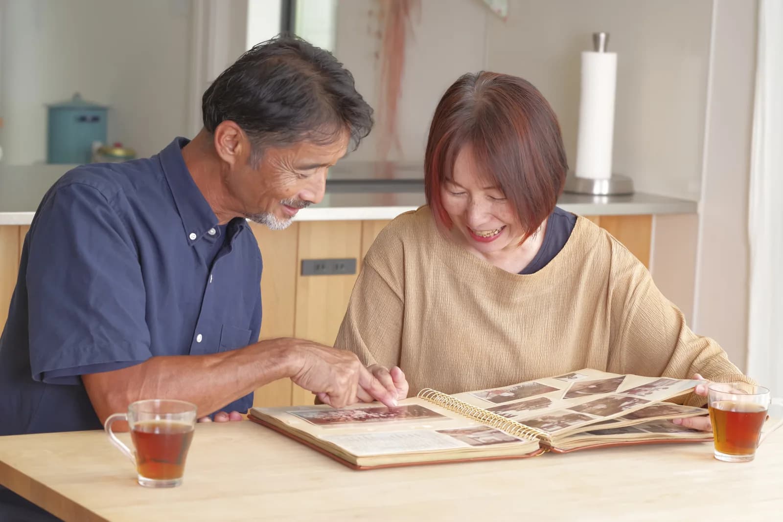 昔のアルバムを見ながら思い出を語るシニア夫婦(実家を手放すときの気持ちの整理に関する記事のイメージ)