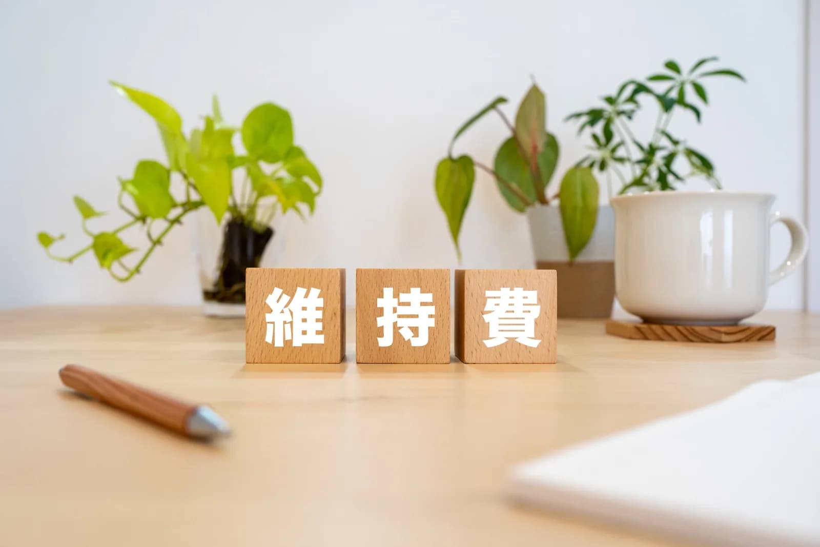 机の上に置かれた「維持費」の文字ブロック(空き家の維持費に関する記事のイメージ)