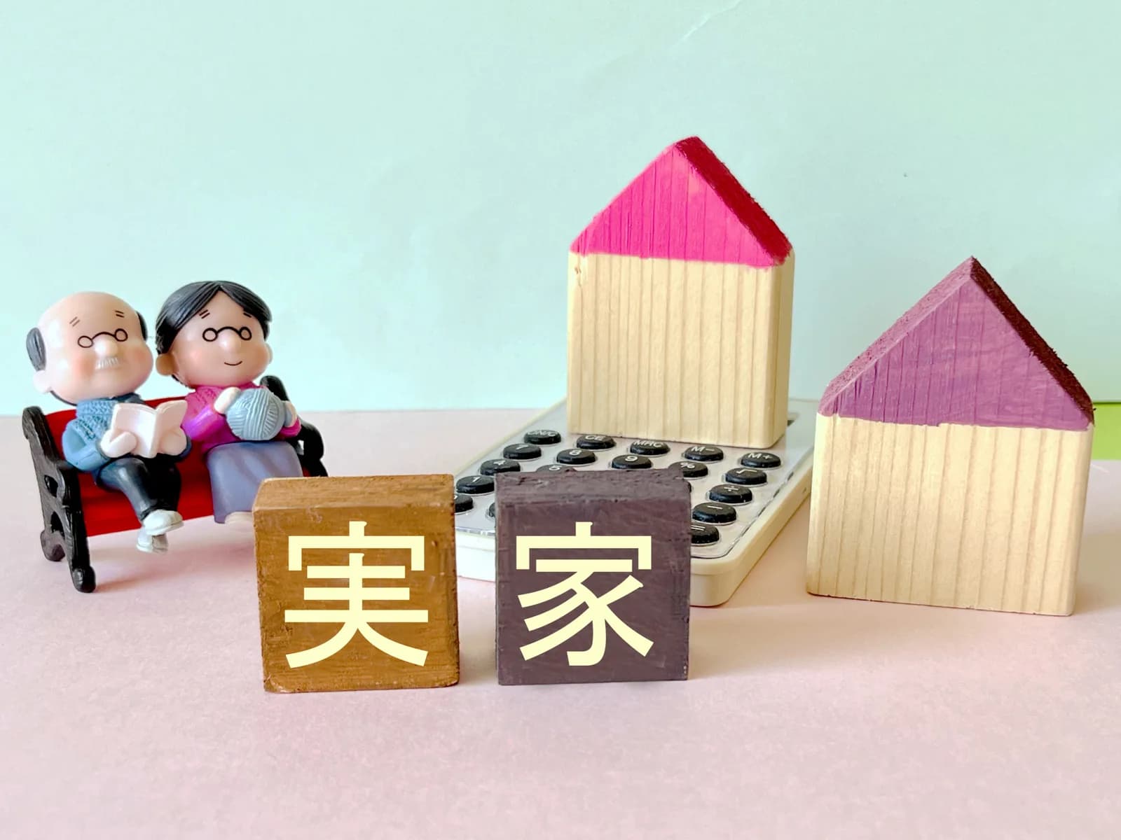 「実家」の文字ブロックと家の模型とシニア夫婦の人形(空き家になった実家に関する記事のイメージ)
