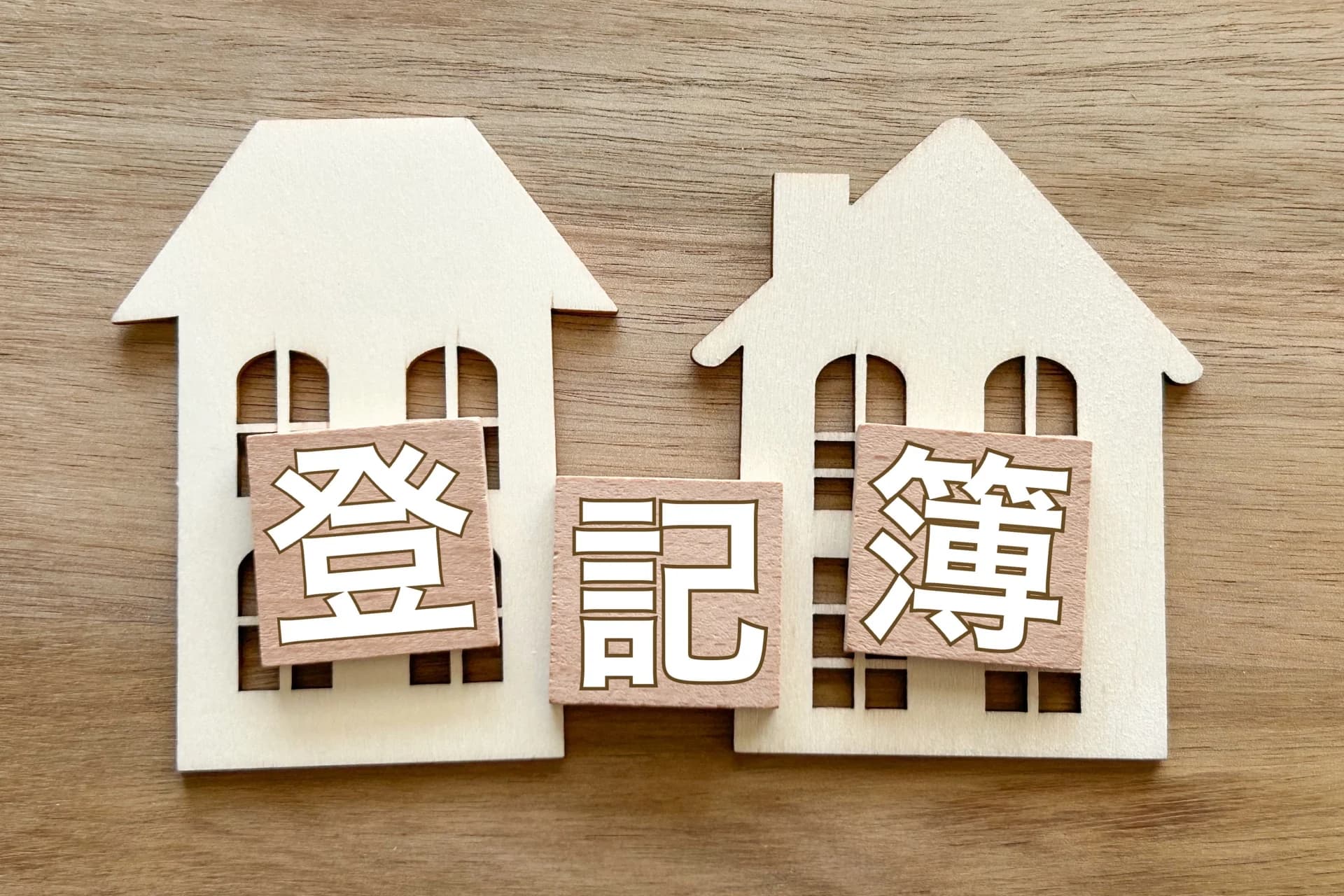 木製の家の切り抜きに「登記簿」の文字タイルを並べた置物(地上権を登記簿で確かめるイメージ)