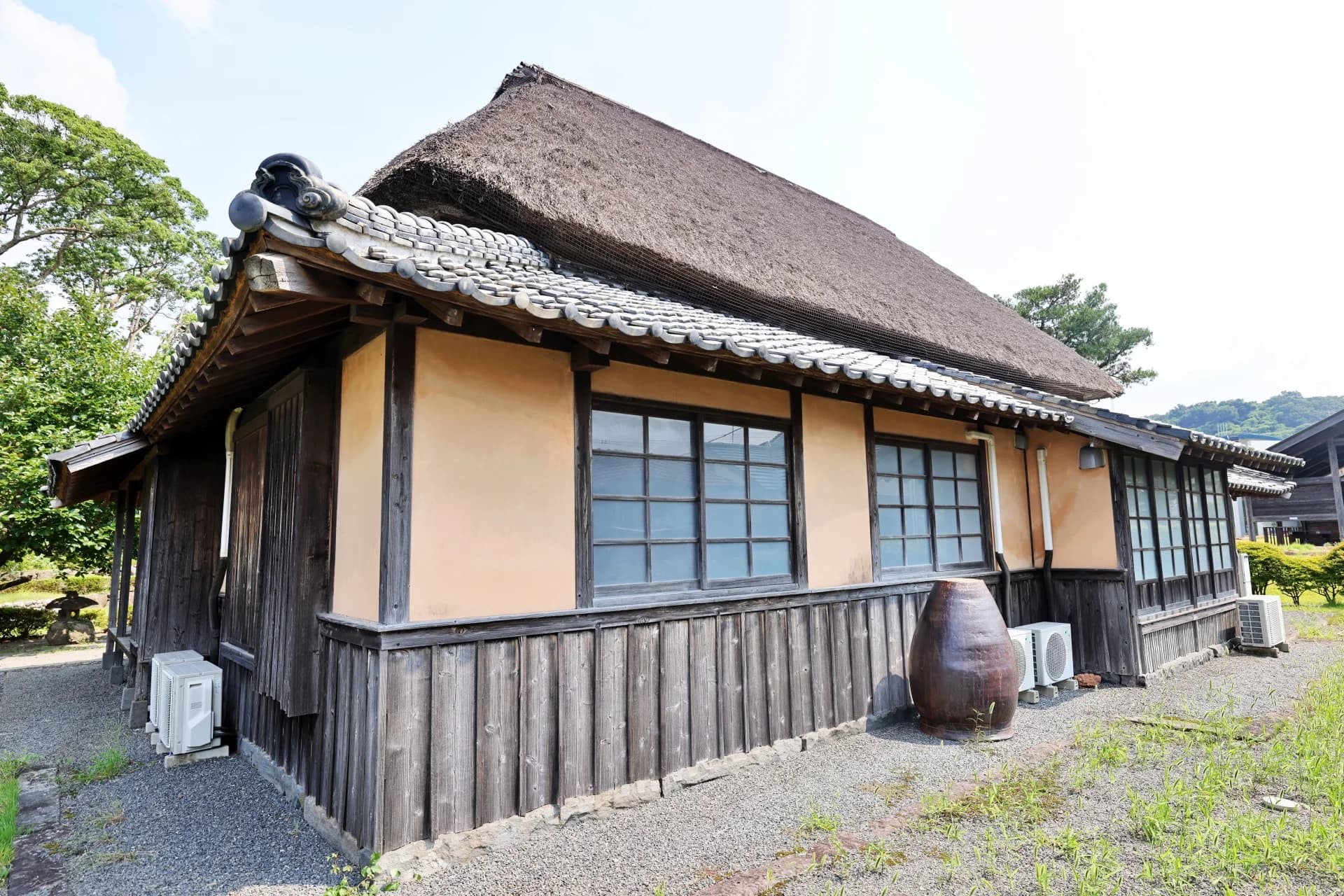 茅葺き屋根に瓦のひさしを付けた土壁の古民家