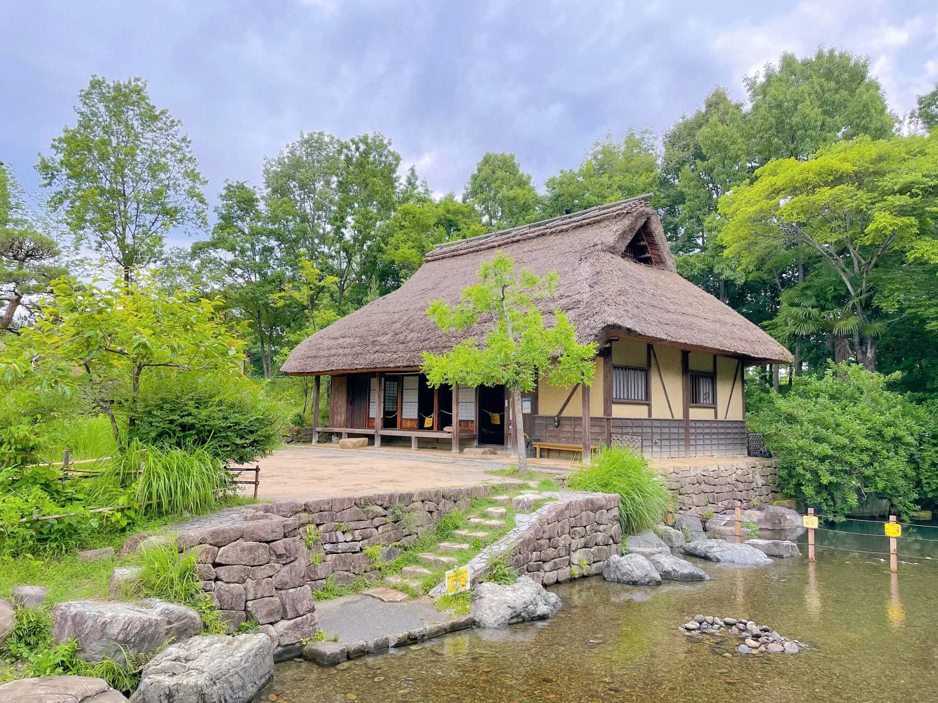 池と石垣のそばに建つ茅葺き屋根の家