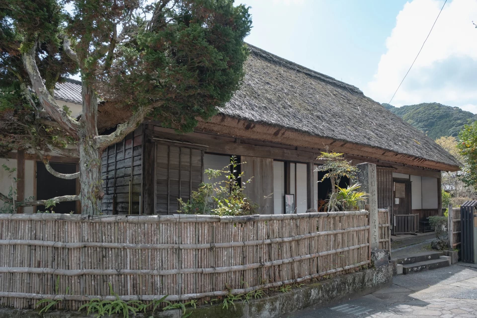 生け垣と木に囲まれた茅葺き屋根の古民家(静岡県下田市の吉田松陰寓寄処)