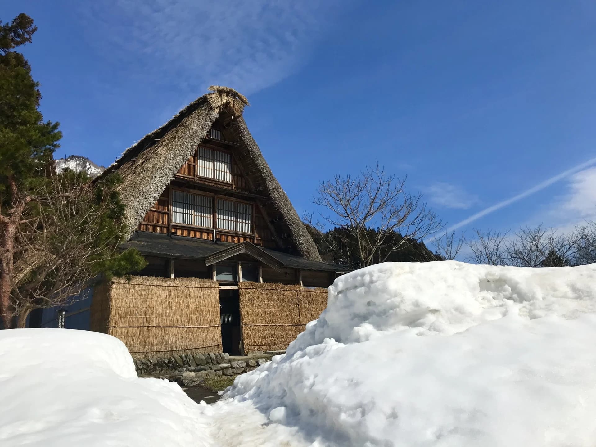 雪の残る茅葺き屋根の家
