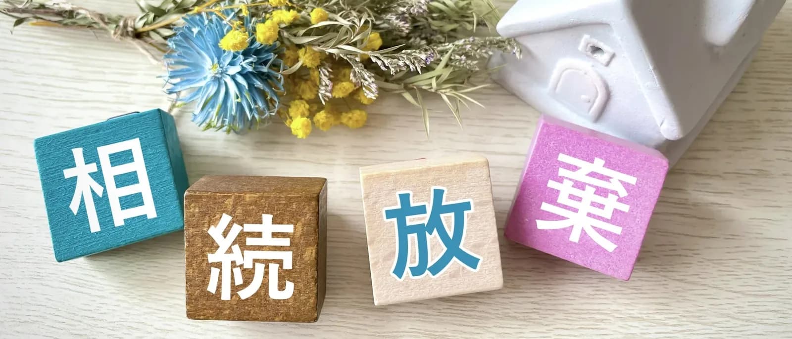 「相続放棄」の文字ブロックと白い家の置物(相続放棄した家に関する記事のイメージ)