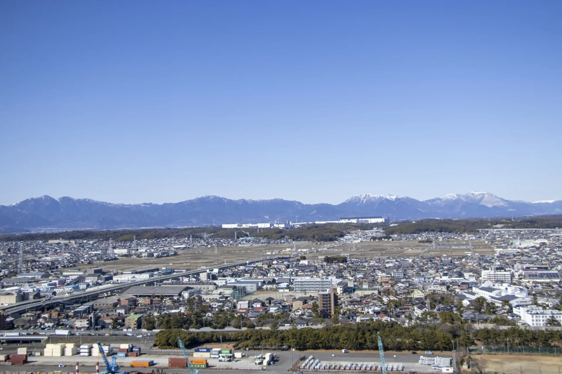 住宅が広がる四日市の街並みと雪をかぶった鈴鹿山脈(三重の共有持分の買取のイメージ)