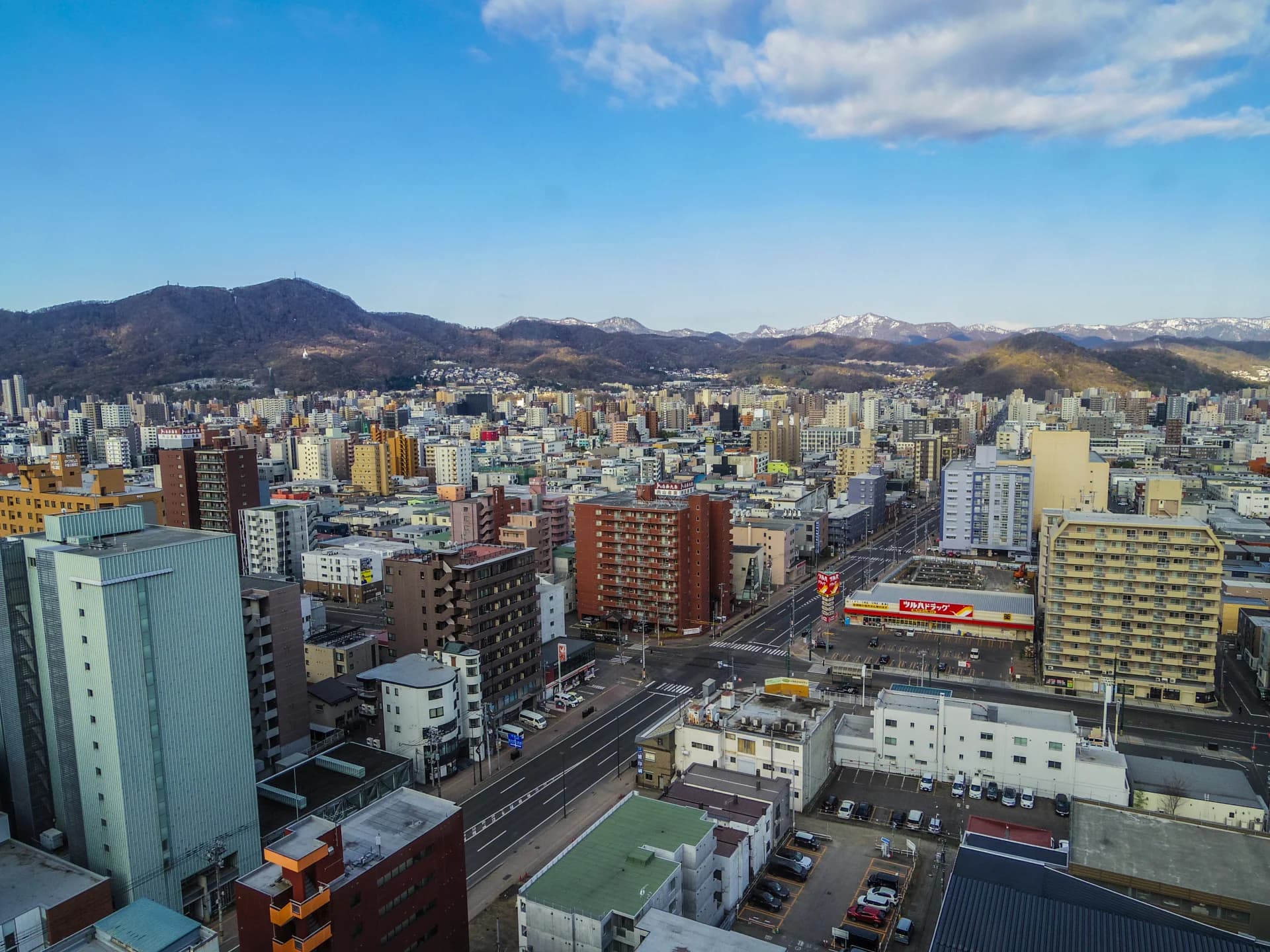 マンションやビルが建ち並ぶ札幌市中央区の街並みと背後の山並み(札幌の共有持分の買取のイメージ)
