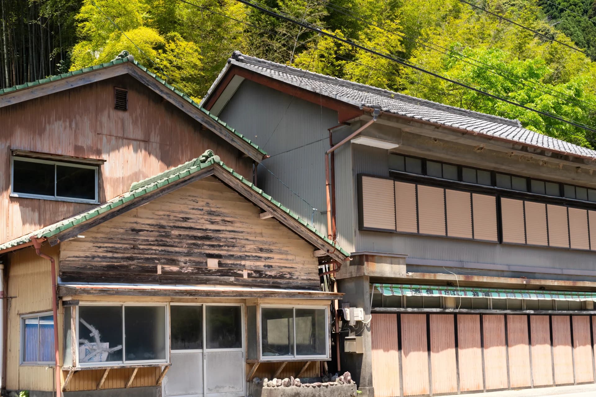 山あいに並ぶ瓦屋根の古い木造家屋(古民家の行き先を考えるイメージ)