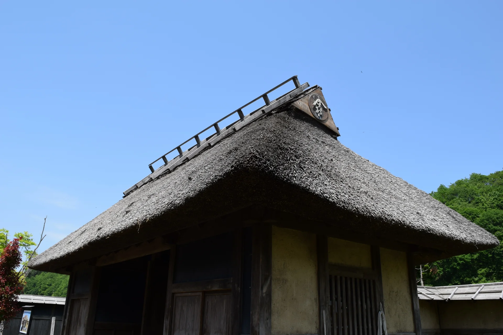 青空を背にした茅葺き屋根の家