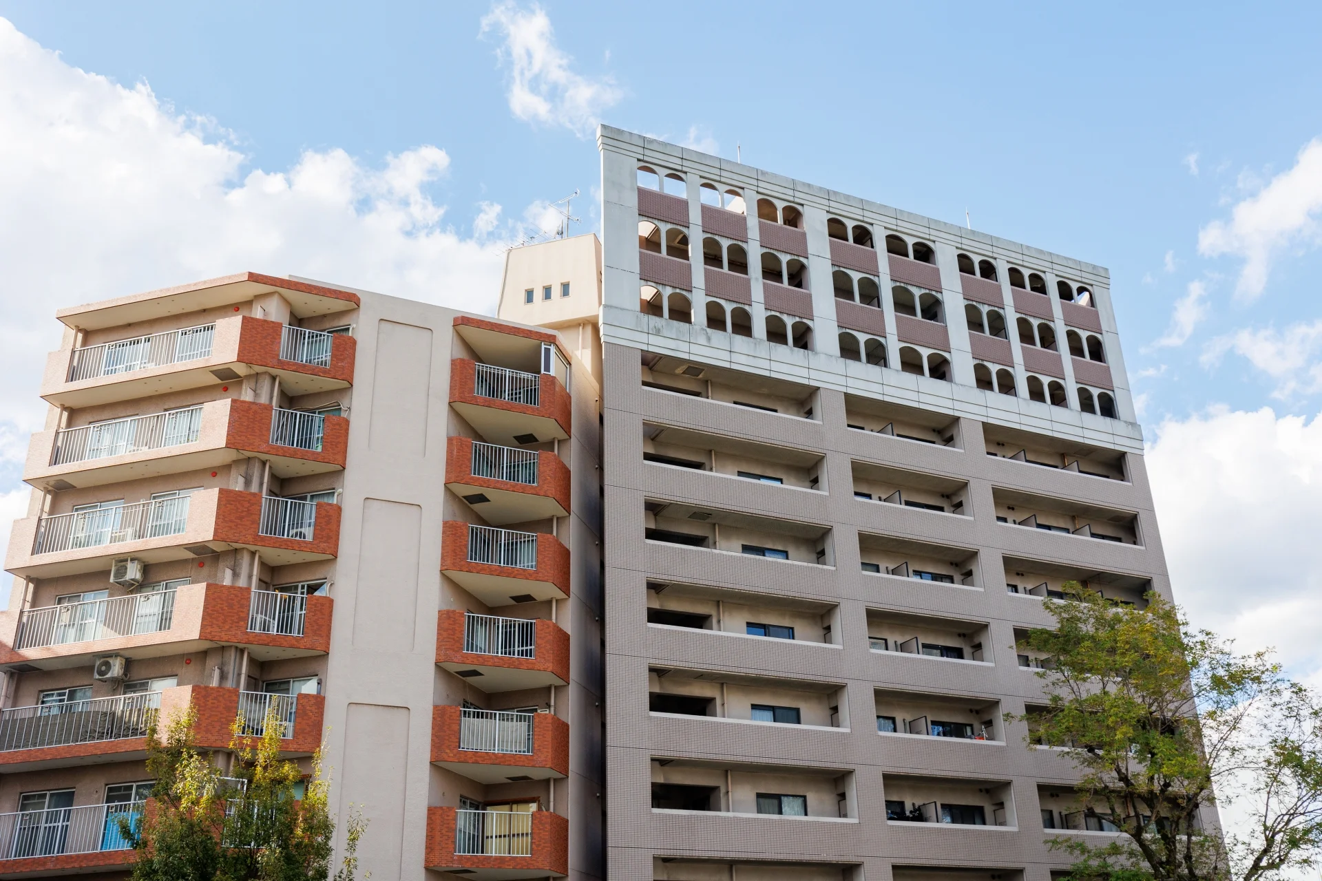 青空の下に並ぶ中層マンションの外観（マンションの部屋と敷地利用権のイメージ）