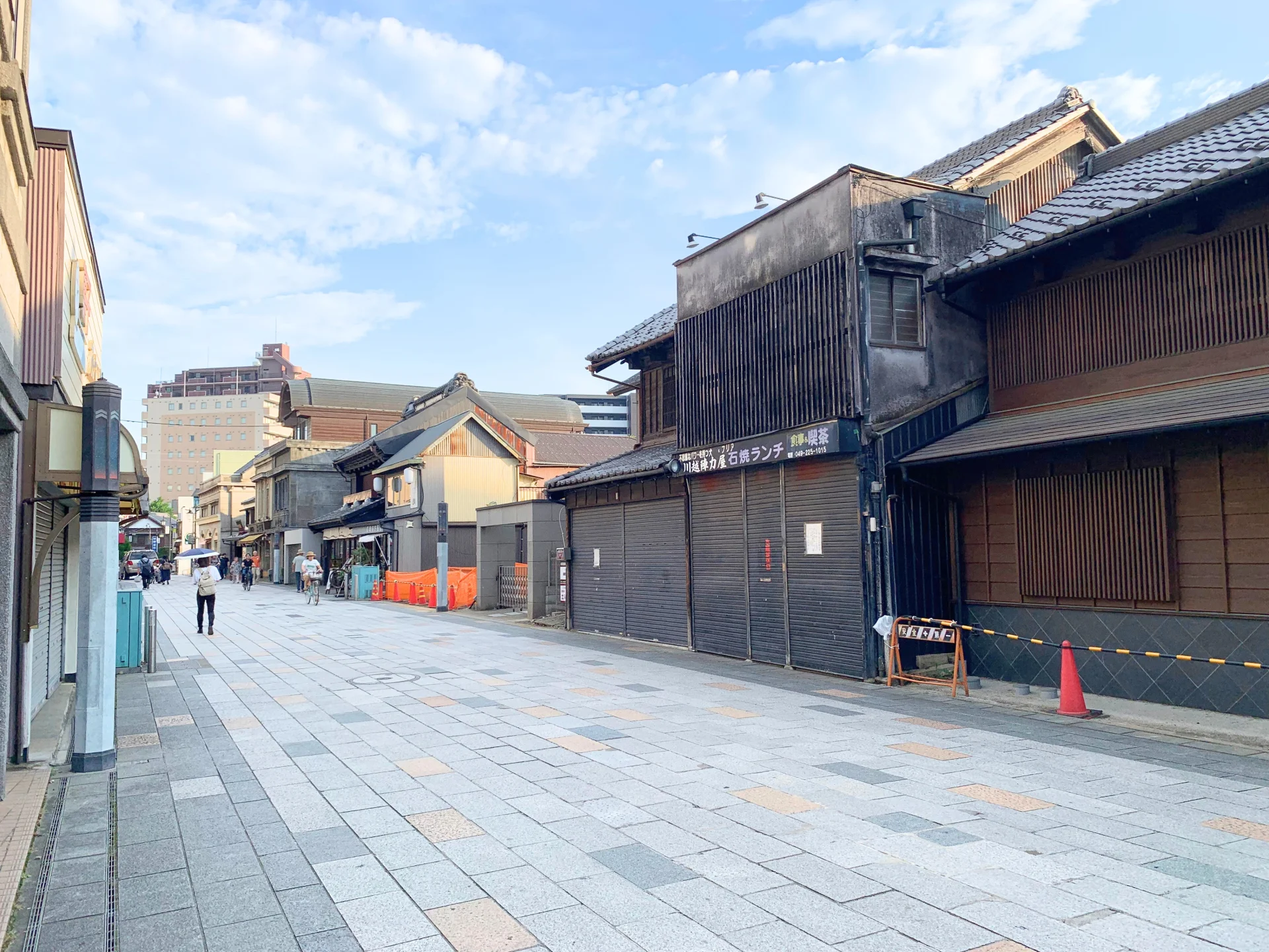 瓦屋根の古い蔵造りの商家が石畳の通り沿いに並び奥にマンションが見える小江戸川越の街並み(川越市の空き家買取のイメージ)