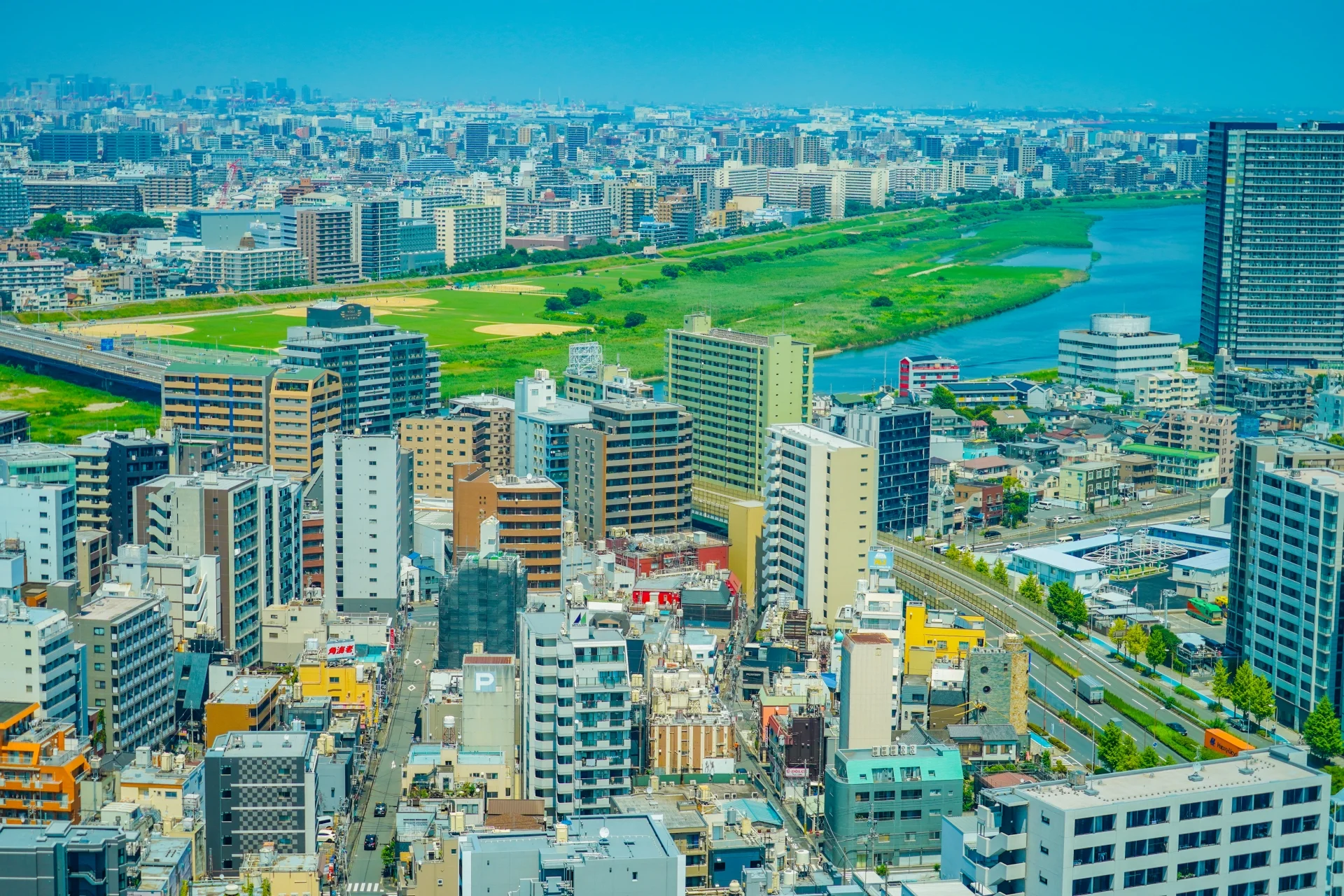 多摩川の河川敷に沿って中高層の住宅とマンションが建ち並ぶ川崎市の街並み（川崎市の空き家買取のイメージ）