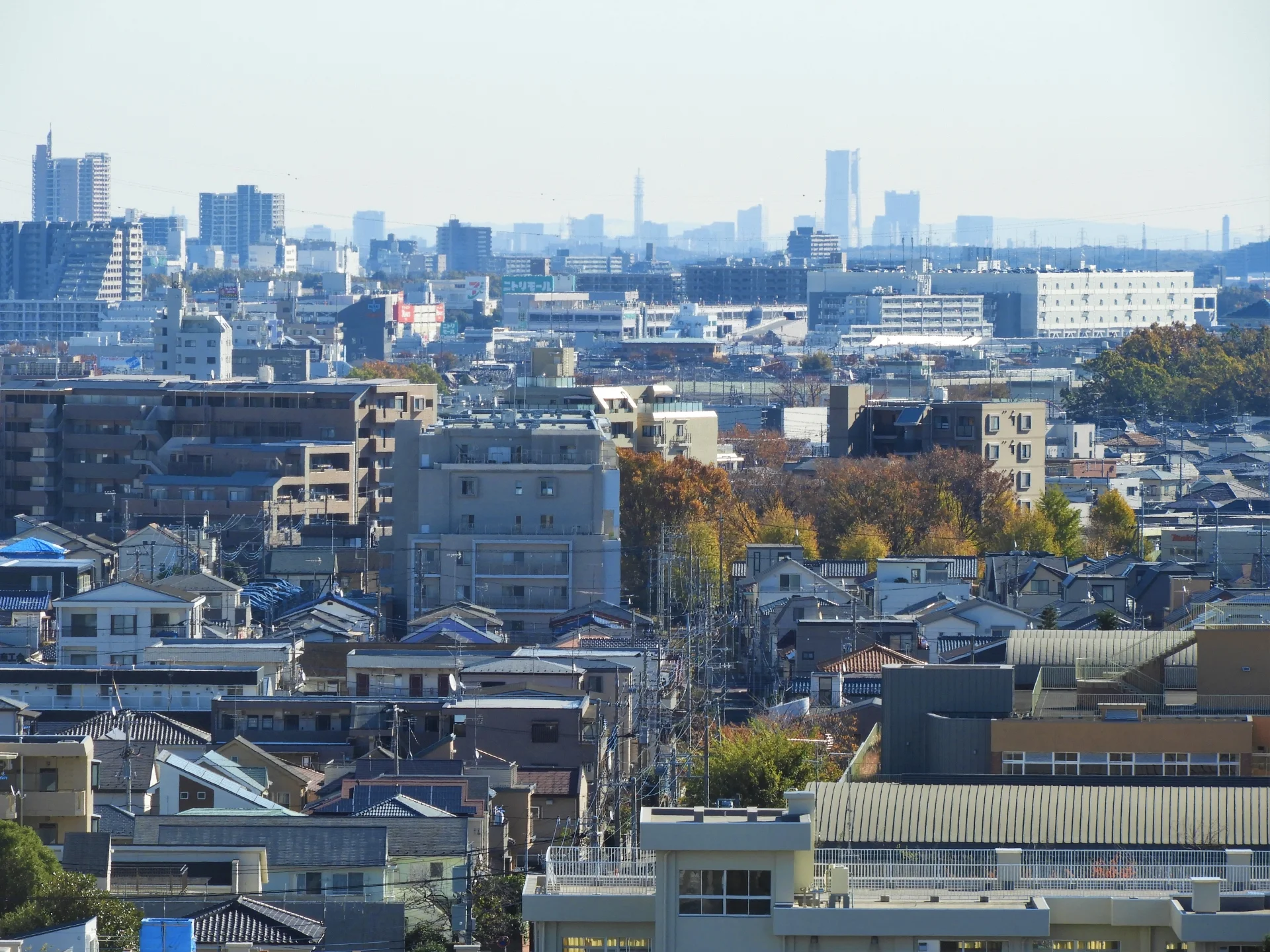 相模原の市街地で戸建て住宅と集合住宅が連なり遠くに横浜の高層ビルが見える街並み（相模原市の空き家買取のイメージ）