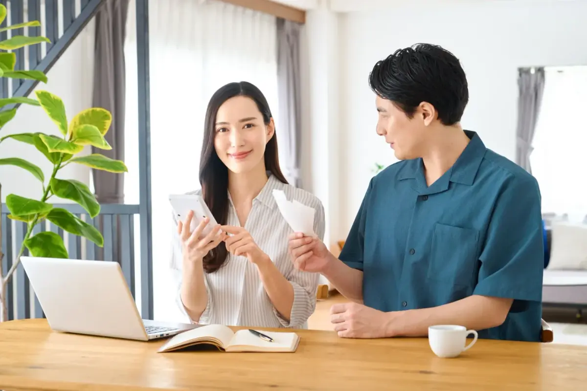 電卓を手に笑顔で家計を相談する夫婦（空き家に関する記事のイメージ）
