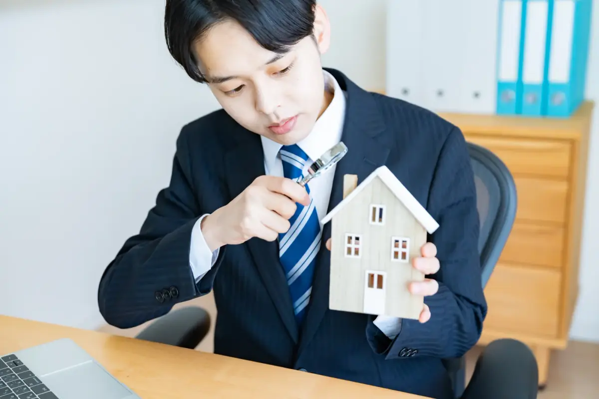 家の模型を持つ男性（不動産買取業者に関する記事のイメージ）