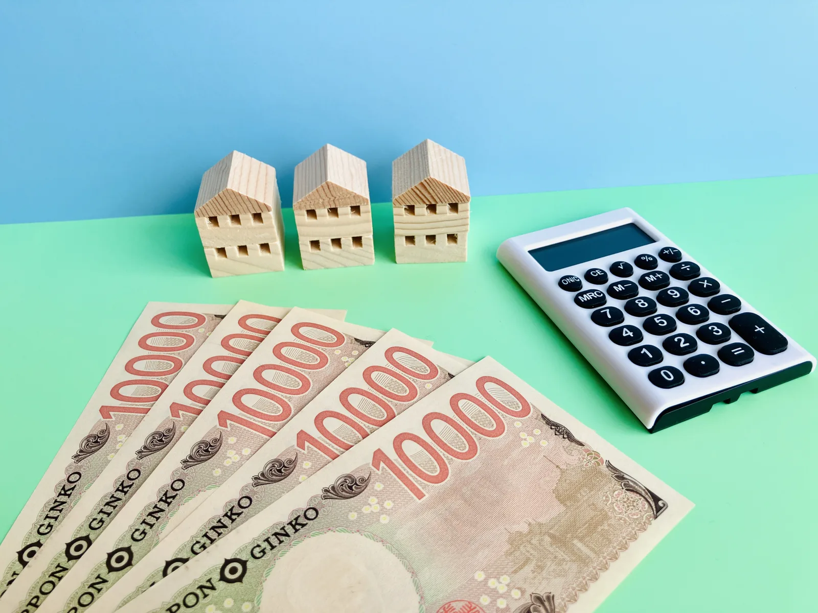 5万円と電卓と3軒の家(不動産の税金に関する記事のイメージ)