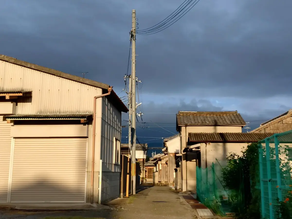 夕日差す古い建物と曇り空が広がる細い路地