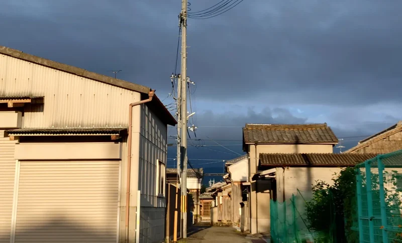 夕日差す古い建物と曇り空が広がる細い路地