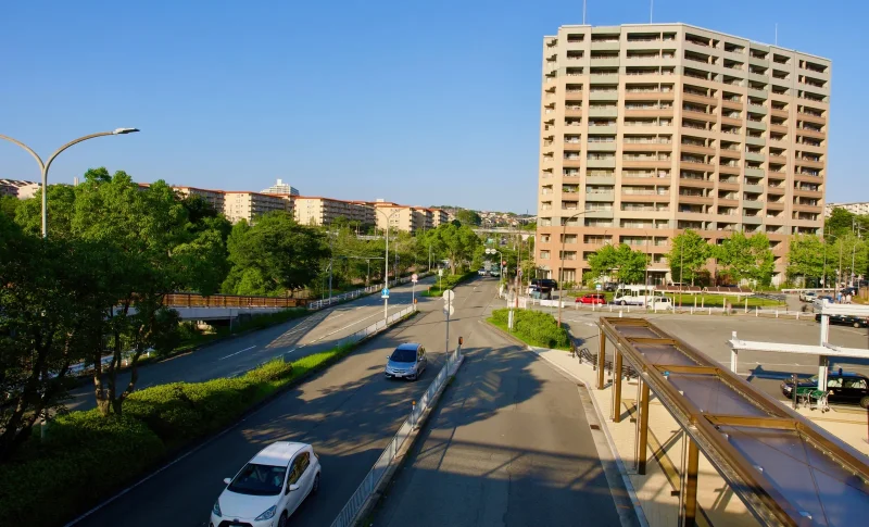 青空が広がる都市の道路とマンション（事故物件に関する記事のイメージ）
