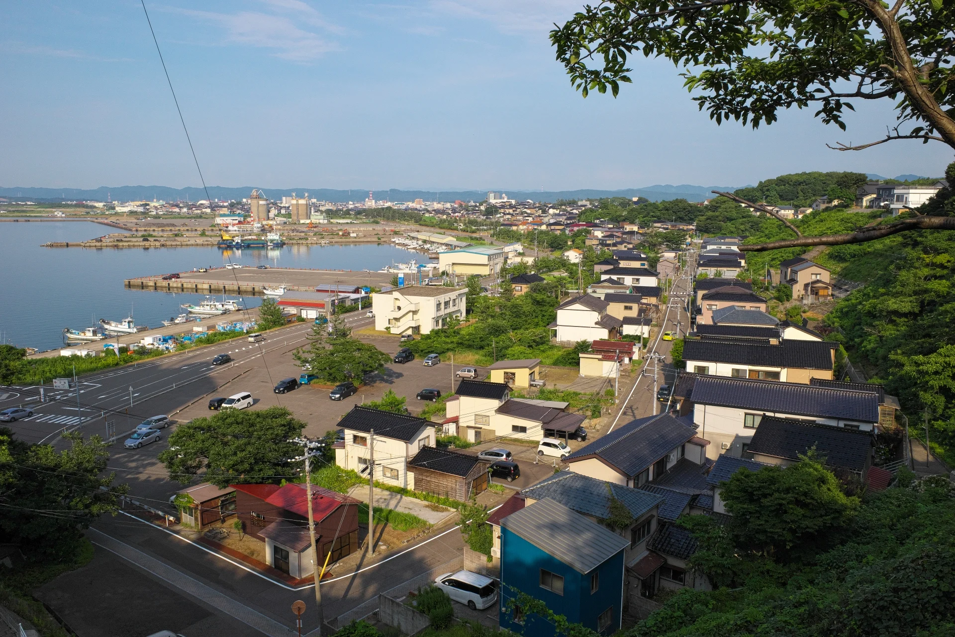 高台から見下ろした柏崎港の手前に瓦屋根の戸建て住宅が建ち並ぶ柏崎市の町並み(柏崎市の0円物件のイメージ)
