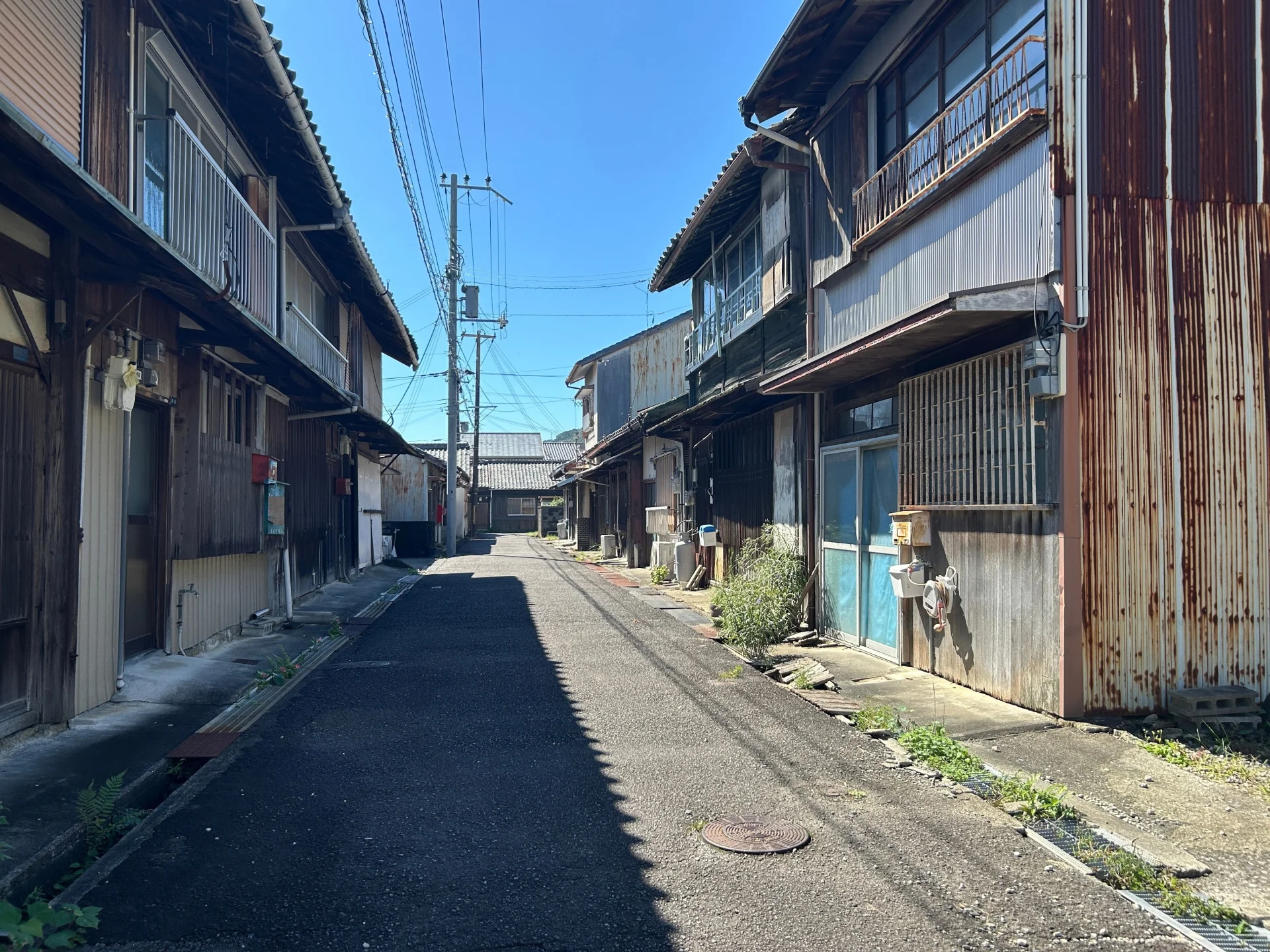 古い木造の二階建て住宅が両側に並ぶ地方の細い通り（竹原市の空き家の無償譲渡のイメージ）